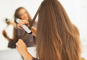 Brunette woman straightening her hair